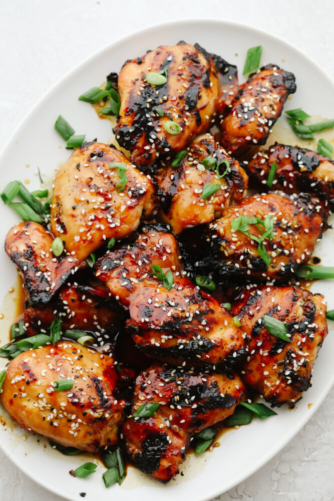 Grilled chicken with honey and garlic on a serving plate with green onions.