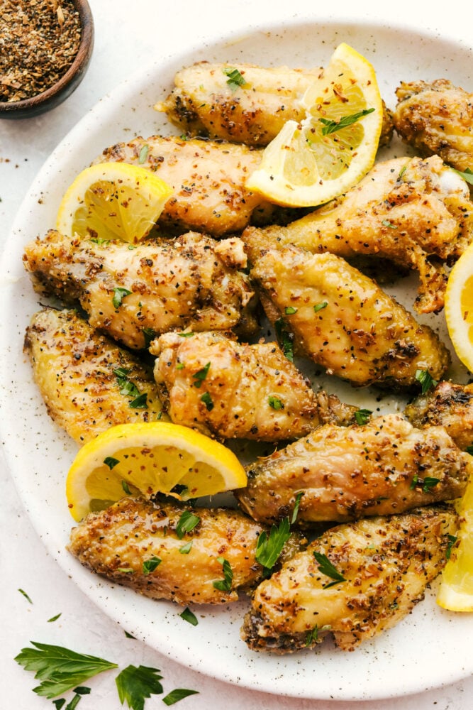 Lemon pepper wings with lemon garnish on the plate.