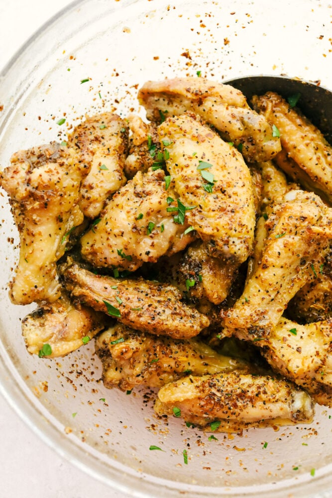 Lemon pepper wings are tossed into a bowl.