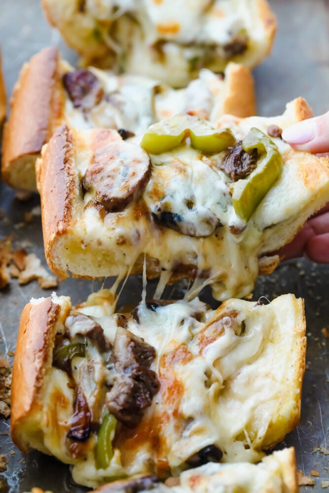 Piece of Philly cheesesteak cheesy bread being pulled from pan