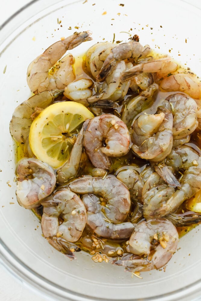 Fresh shrimp in marinade with lemon slices.