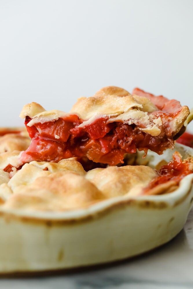 Slice being taken out of strawberry rhubarb pie.