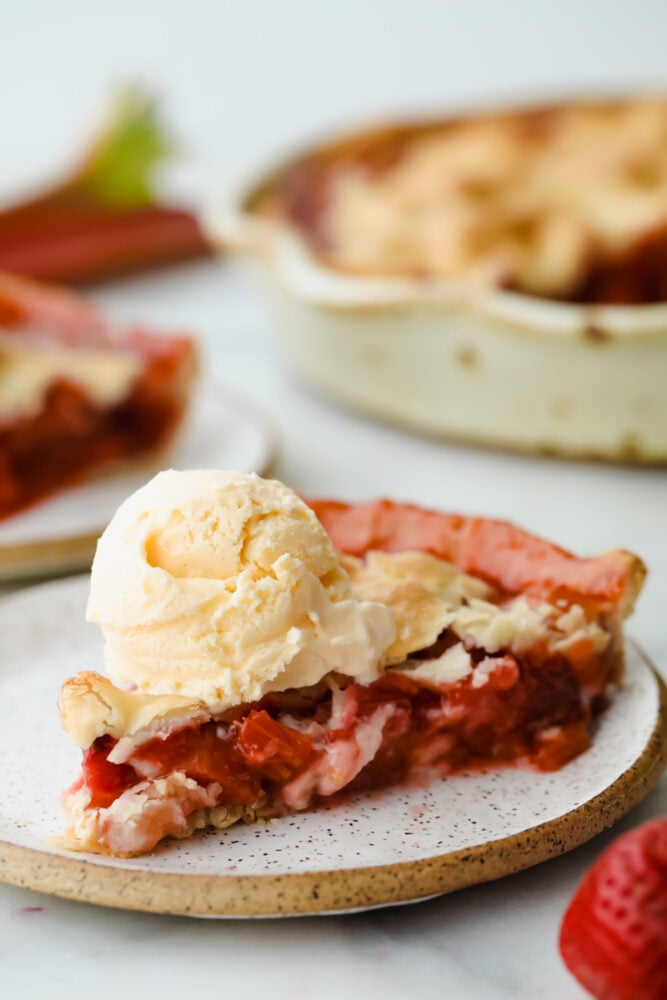 Slice of strawberry rhubarb pie with a scoop of vanilla ice cream on top