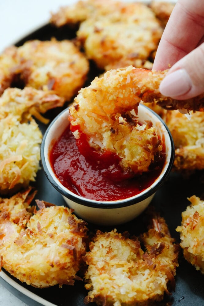 Air fried shrimp being dipped into sauce.