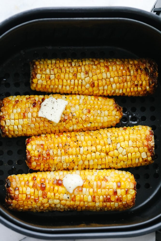 Air Fryer corn on the cob in the basket with butter. 