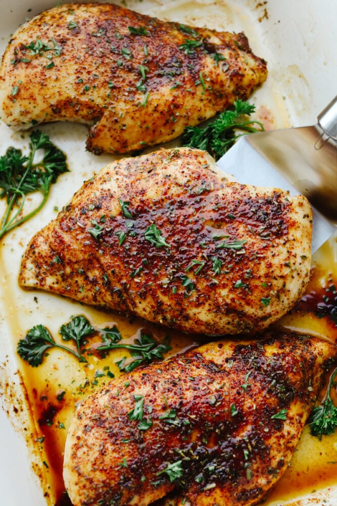 Baked chicken being served from a platter. 