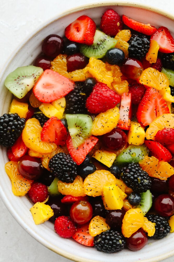 Mixed summer fruits with poppyseed dressing in bowl.