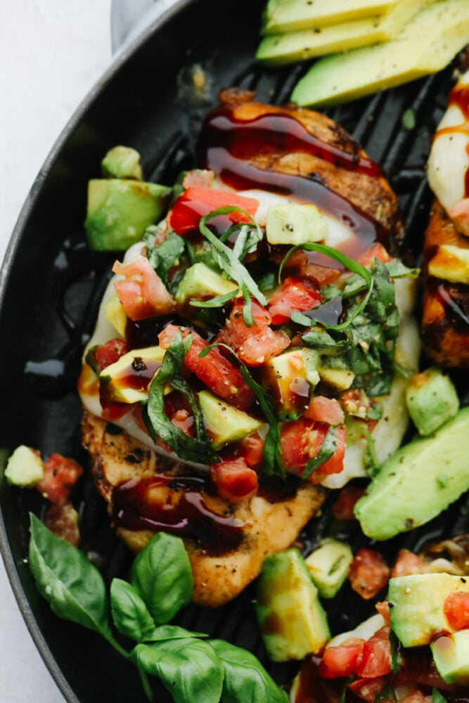 Upclose picture of chicken topped with the avocado salsa and basil. 