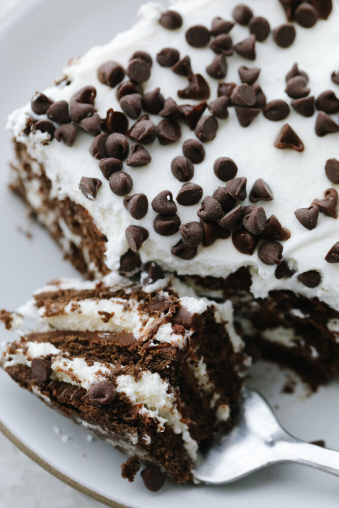A slice of chocolate icebox cake cut with a fork. 