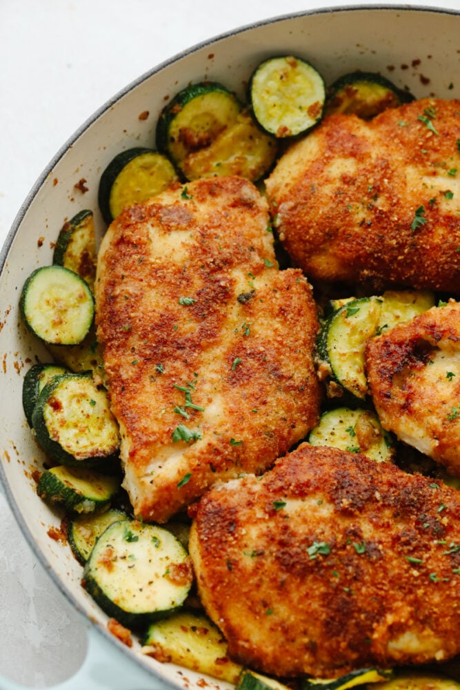 Cooked parmesan garlic chicken and zucchini in a white bowl.