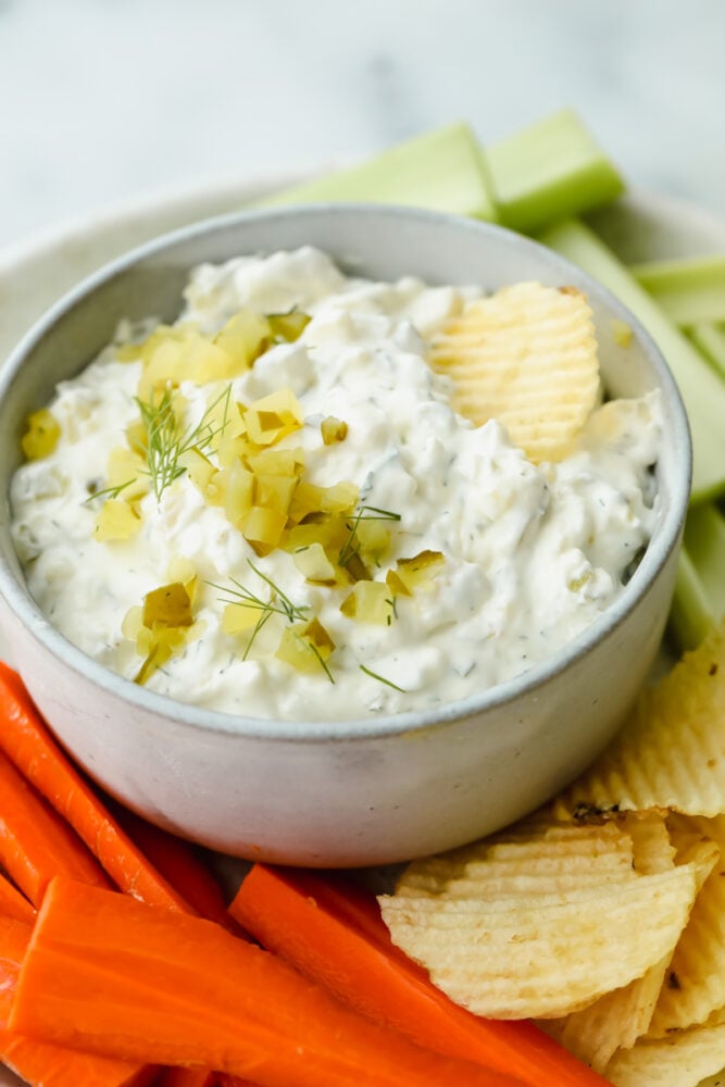 Dill pickle dip with potato chips, celery, and carrots.