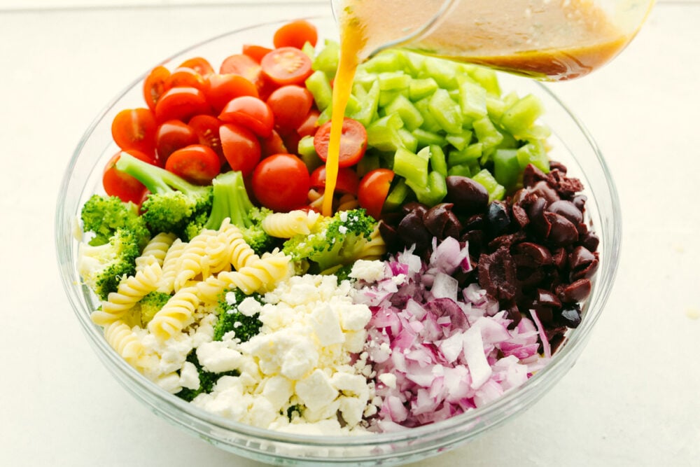 Pouring dressing over pasta salad.