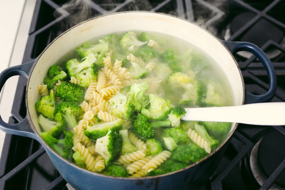 Boiling broccoli and pasta in a pot.