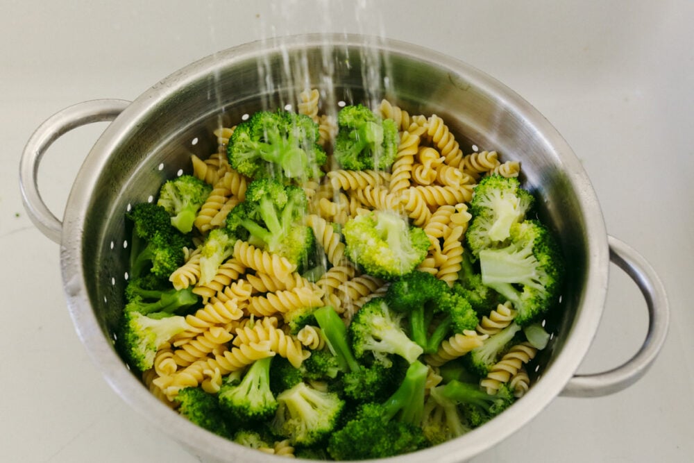 Straining veggies and pasta and rinsing with cold water.