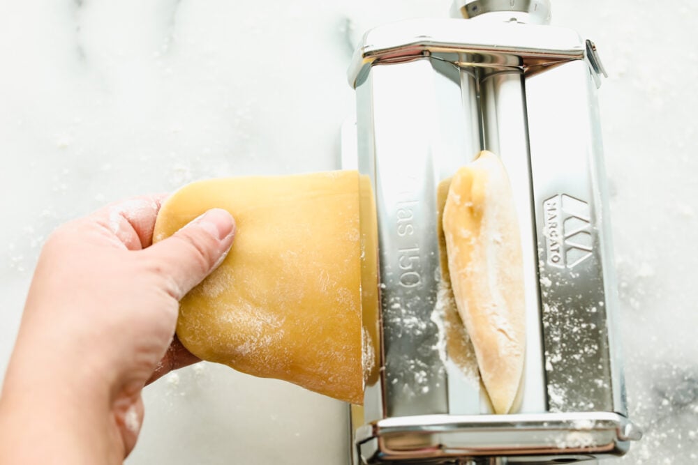 Feeding the dough into a pasta roller. 