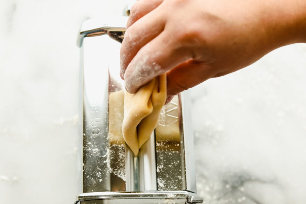 Feeding the folded pasta into the pasta maker. 