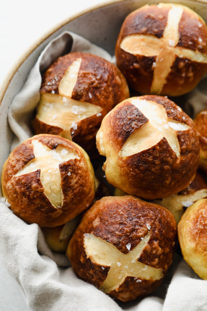 Pretzel Rolls topped with coarse salt in a bowl.