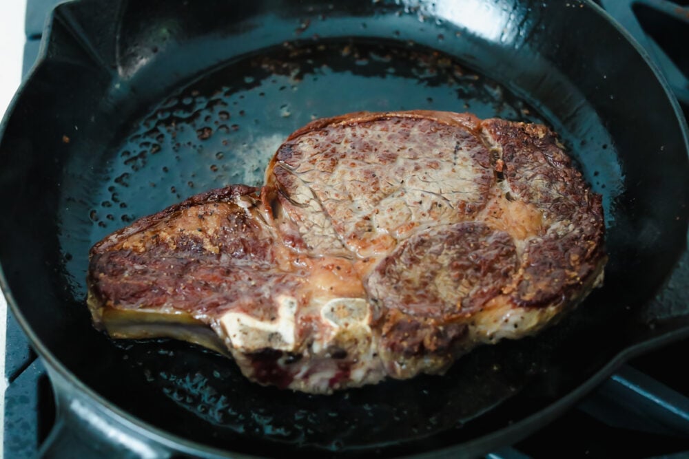 Cooking ribeye steak in a skillet.