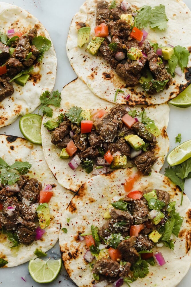 Tortillas being topped with steak and taco toppings.
