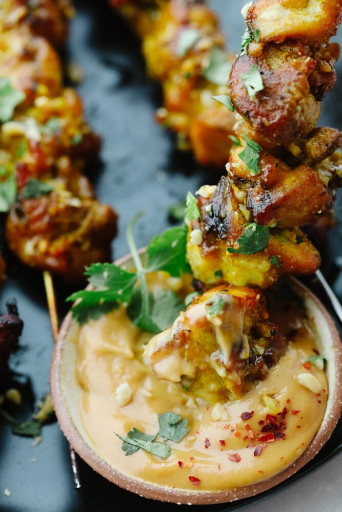 Dipping the chicken in homemade peanut sauce. 