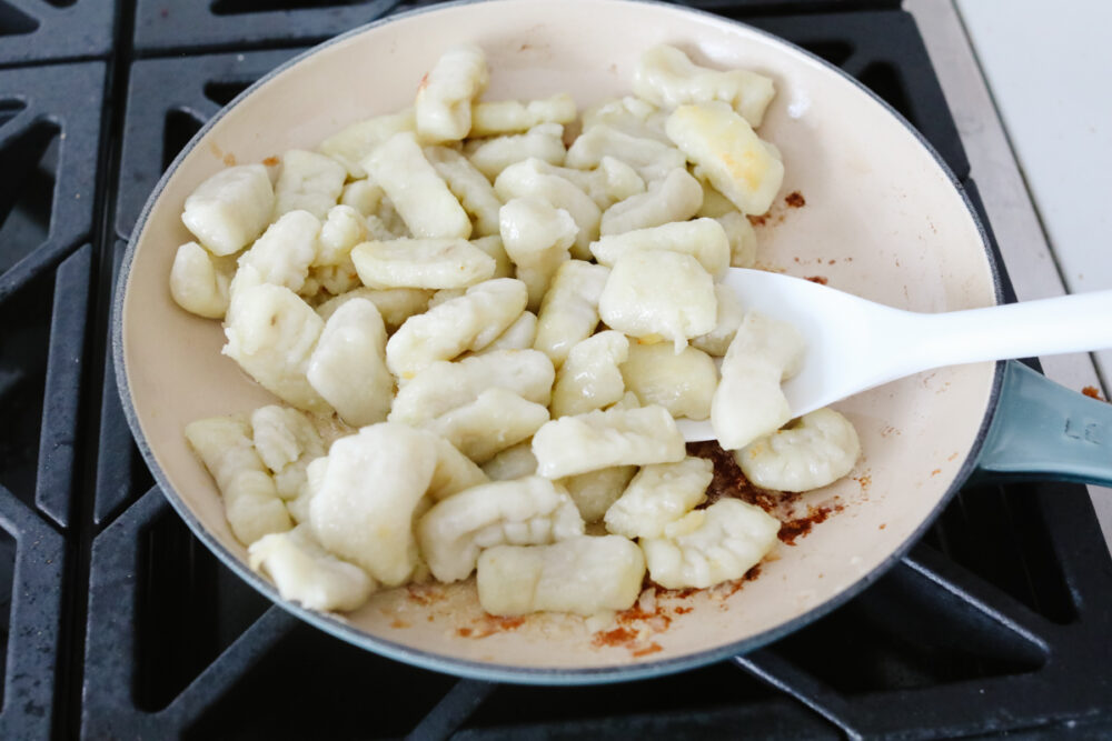 Bolognese Gnocchi is everything that you would hope for in an amazing Italian dish! Flavorful, bold, and full of delightful texture, this tried and true recipe is something that will definitely get you a "WOW!" from your family and friends! Gnocchi being fried in a pan.