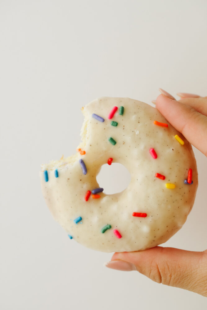 A cake donut being held that is half eaten.