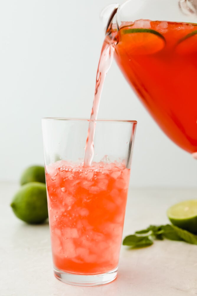 Pouring limeade into a glass.