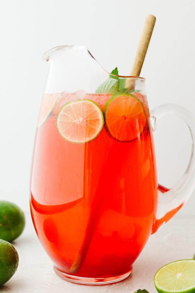 Cherry limeade in a pitcher with lime and mint garnish.