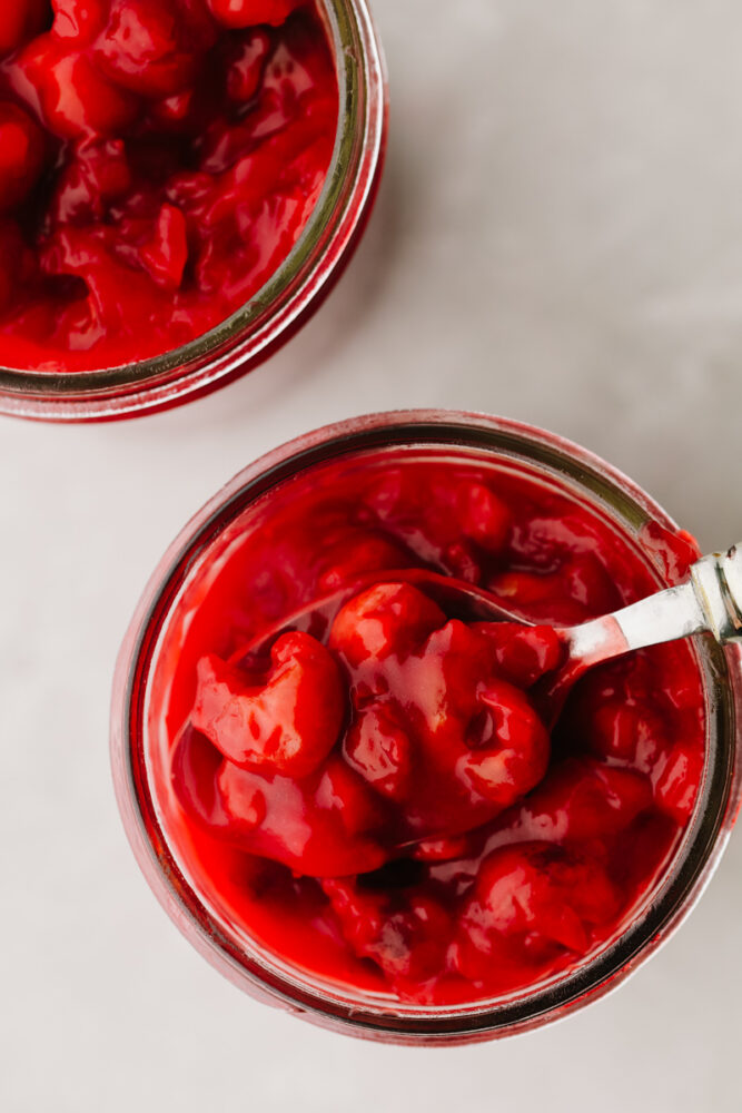 Cherry pie filling in a jar with a spoon. 