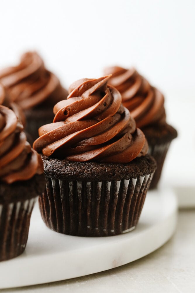 Frosted chocolate cupcakes on a serving dish.