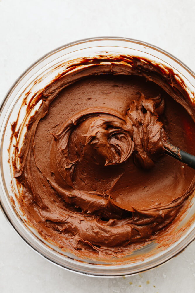 Chocolate buttercream frosting in a bowl stirred together. 