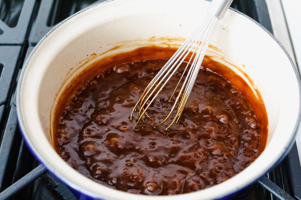 Whisking sauce ingredients together on the stove.