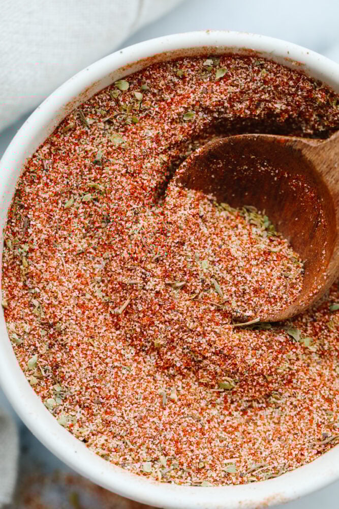 Cajun seasoning is the perfect blend of spices to add a little zest to your dish. Completely versatile and delicious, this homemade spice can be added to a wide variety of recipes giving them just the yummy kick you were looking for! Cajon seasoning being dished with a spoon.
