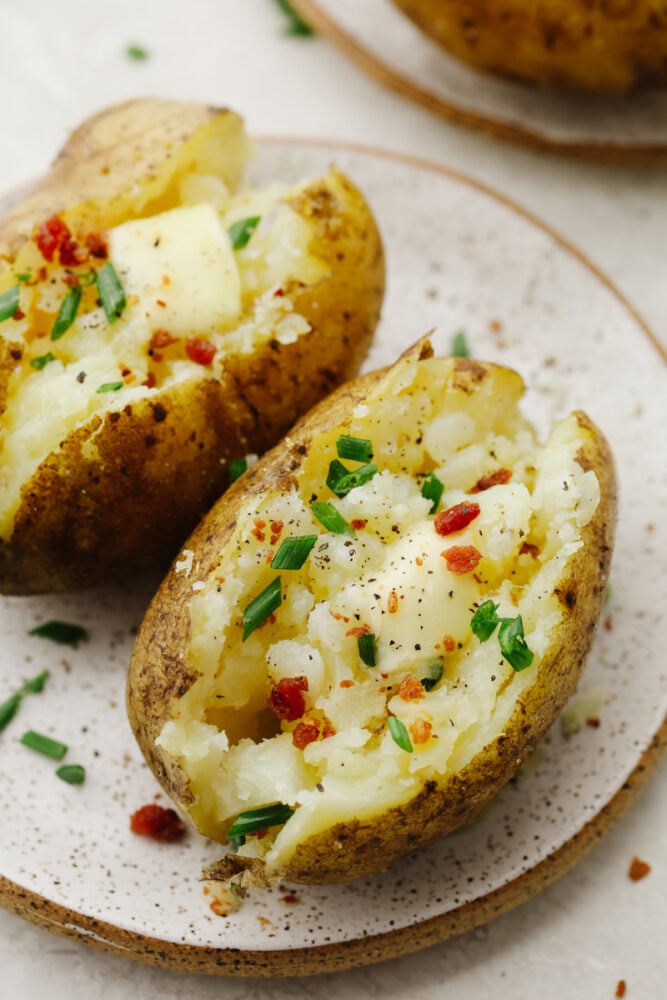 Baked potatoes topped with butter, chives, and bacon bits.