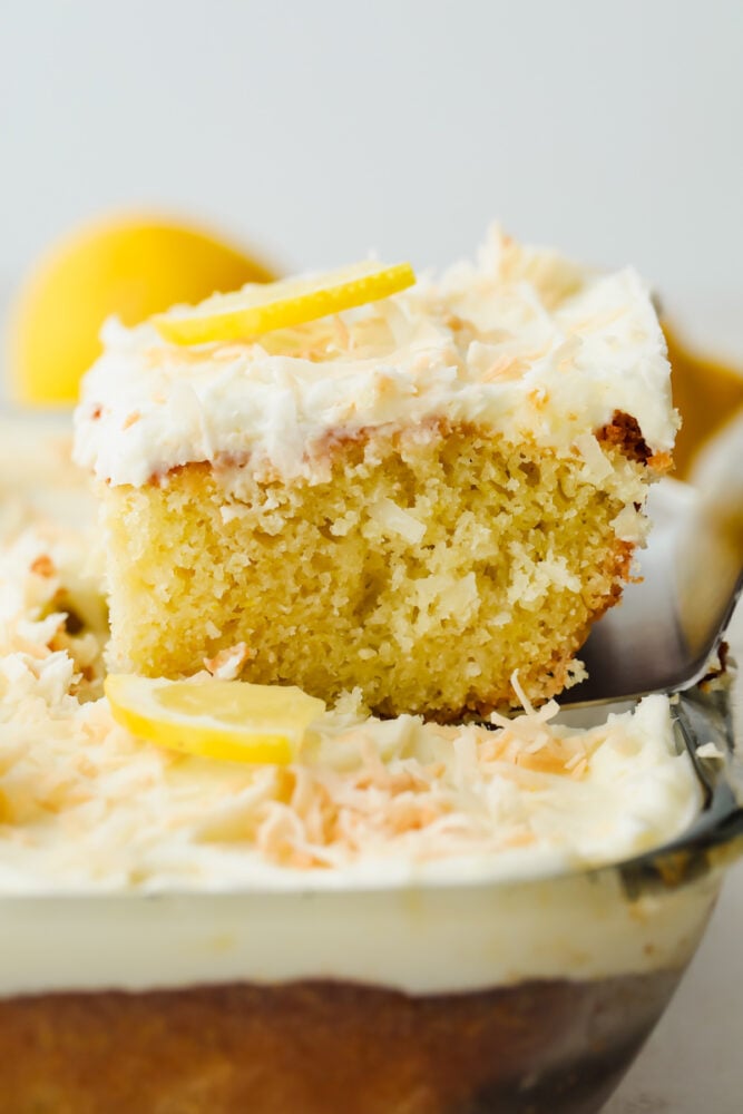 A slice of lemon coconut cake being sliced and taken out of the pan. 