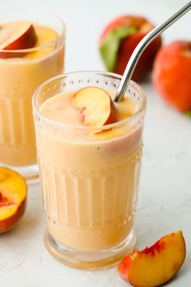 Smoothie with a peach and a straw. 