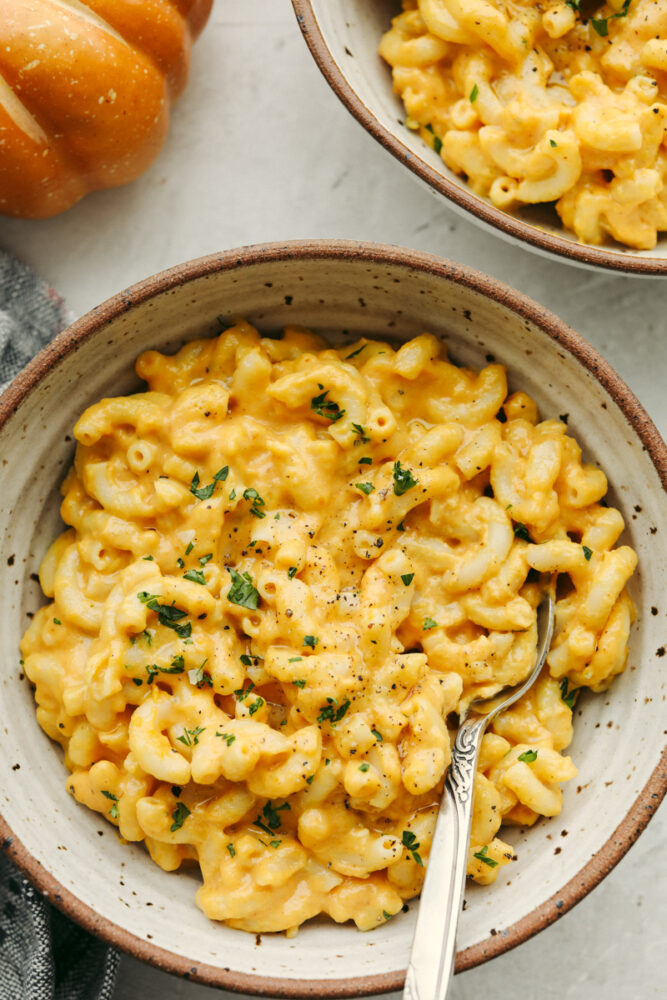 Pumpkin mac and cheese in a bowl with a spoon. 