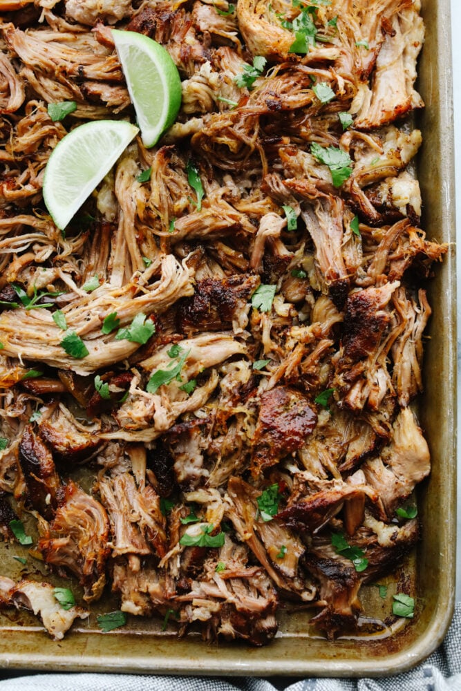 Shredded pork in a pan with a lime. 