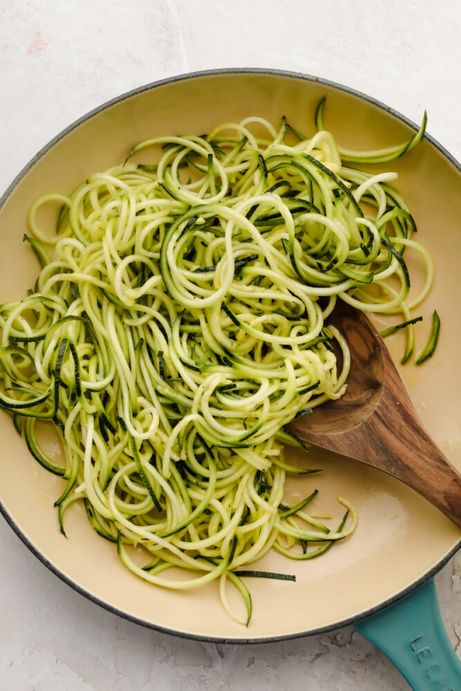 Zucchini noodles in a white skillet.