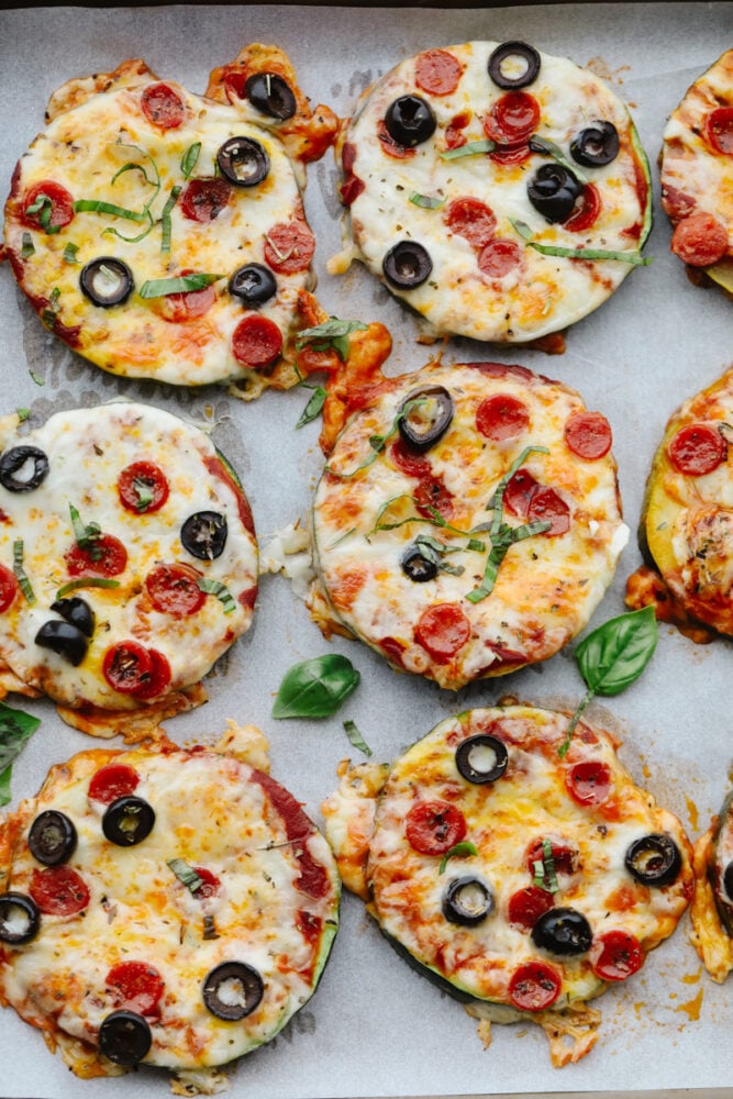 Zucchini pizza bites on a baking sheet lined with parchment paper.