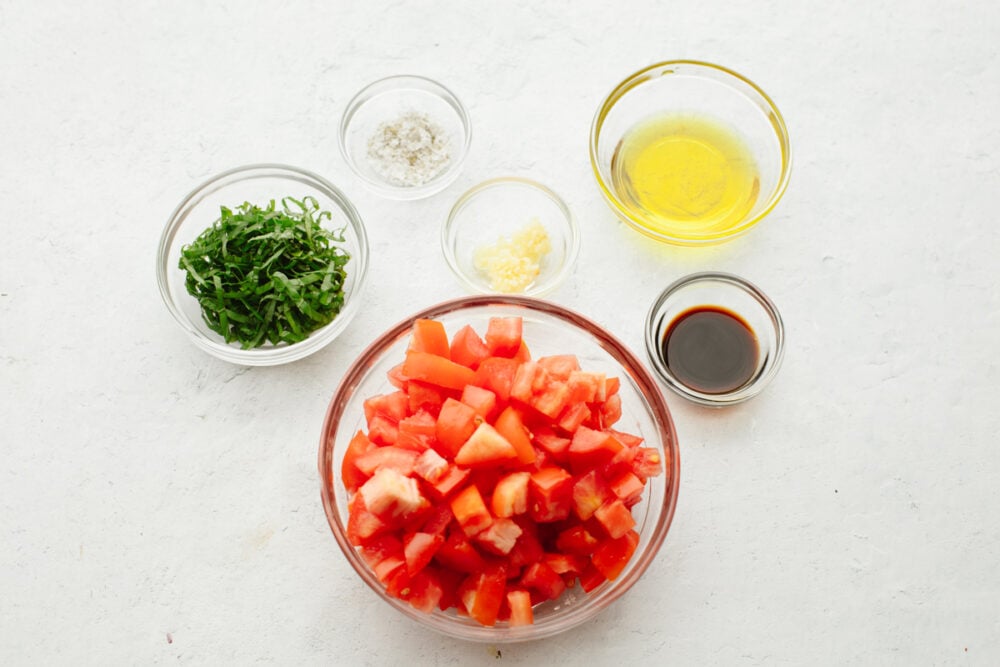 Bowls of chopped tomatoes and vinaigrette ingredients.