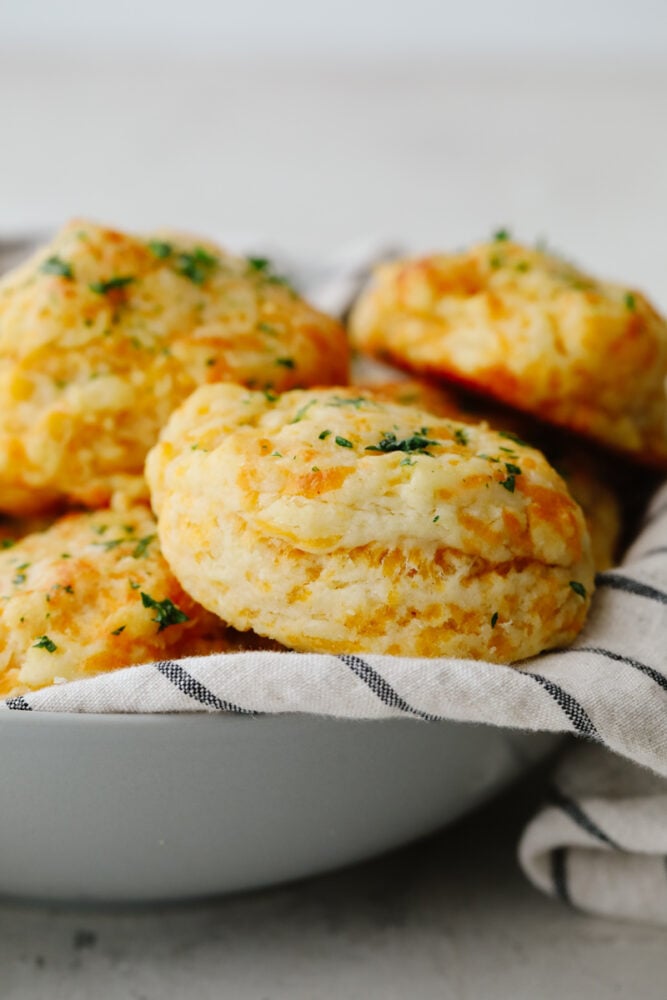 A stack of cheddar biscuits in a gray bowl.