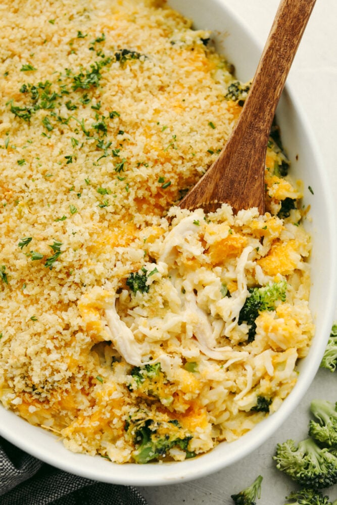 Broccoli, chicken and rice casserole with a wooden serving spoon in it. 