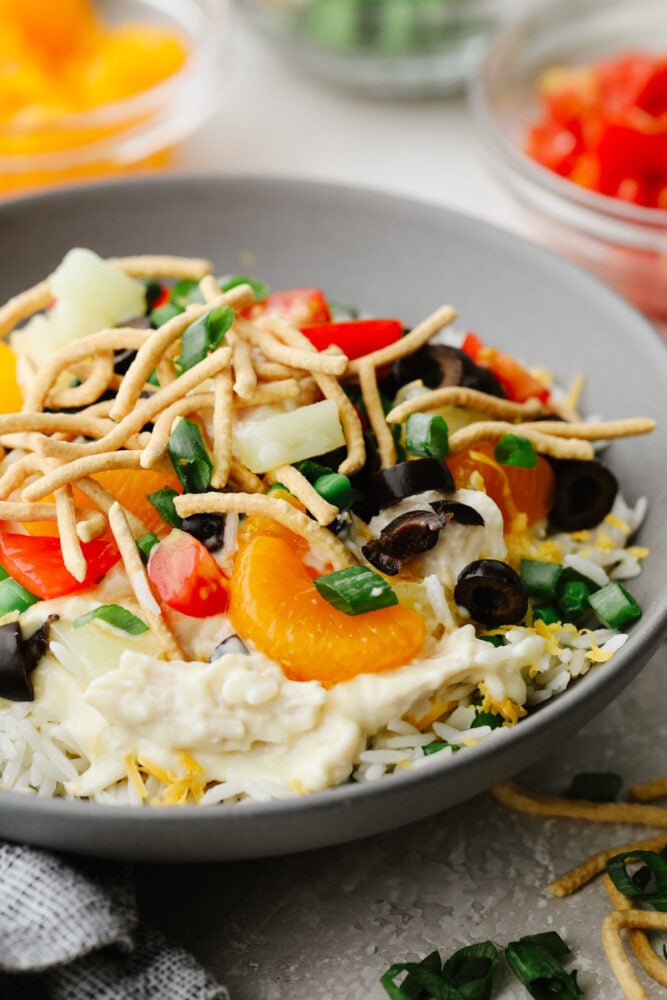 A Hawaiian haystack topped with various toppings in a gray bowl.