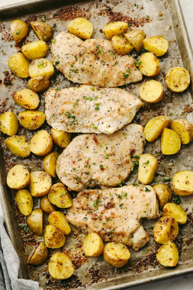 Chicken and potatoes on a baking sheet. 