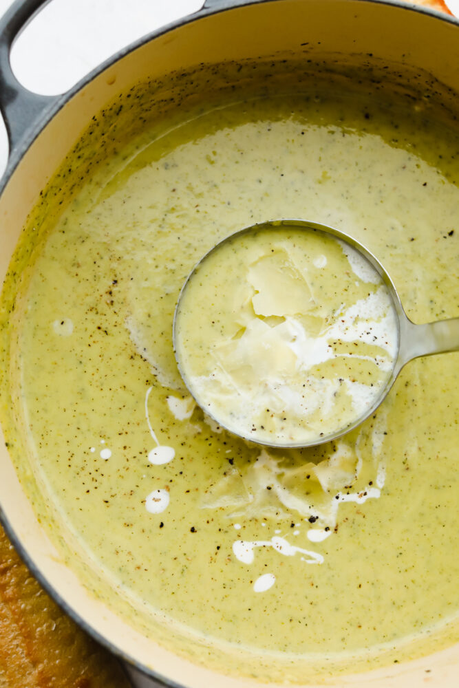Scooping creamy zucchini soup with a ladle.