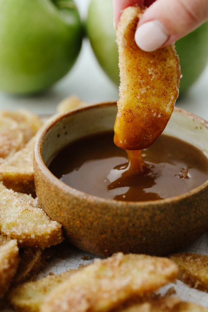 Dipping apple fry in caramel sauce.