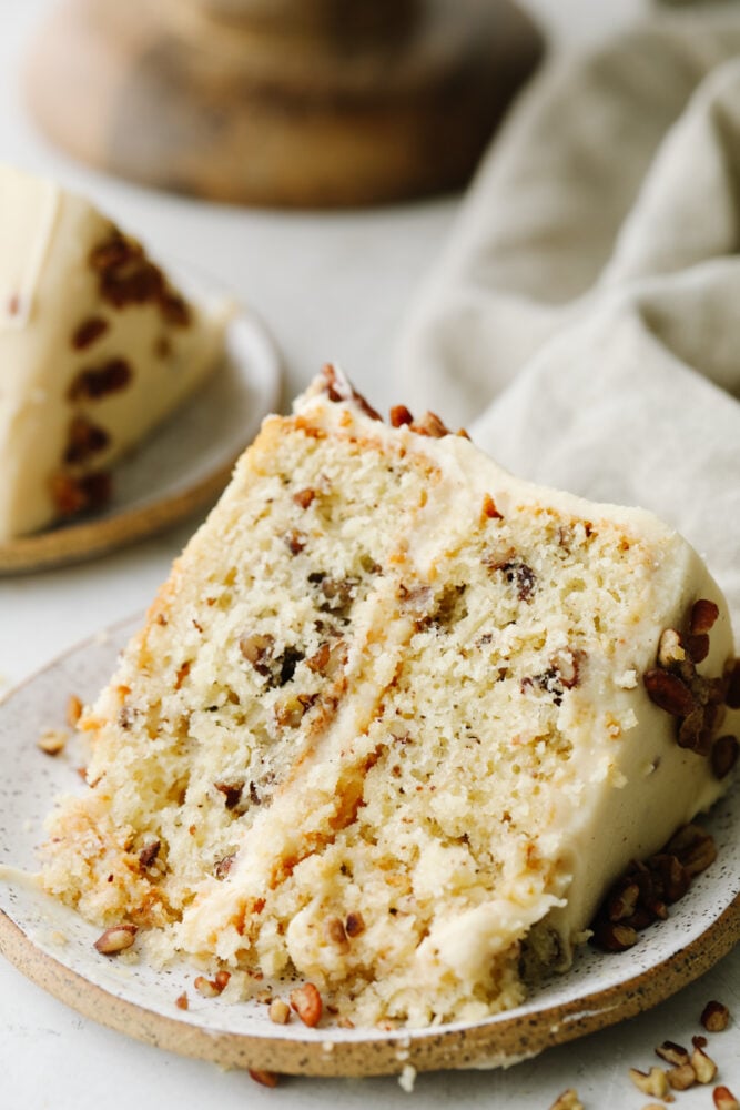 A slice of butter pecan cake on a small stoneware dish.