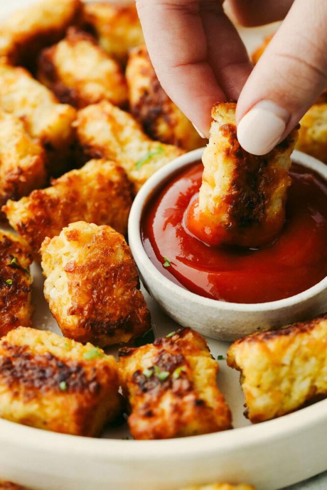A cauliflower tot being dipped into ketchup. 