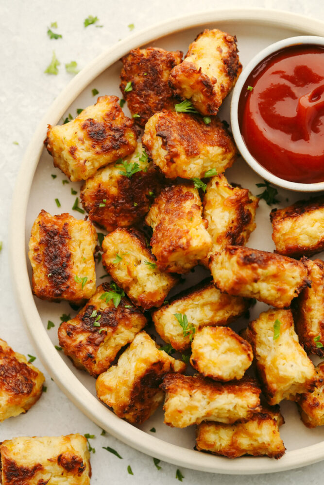 A platter of cauliflower tots with some ketchup. 
